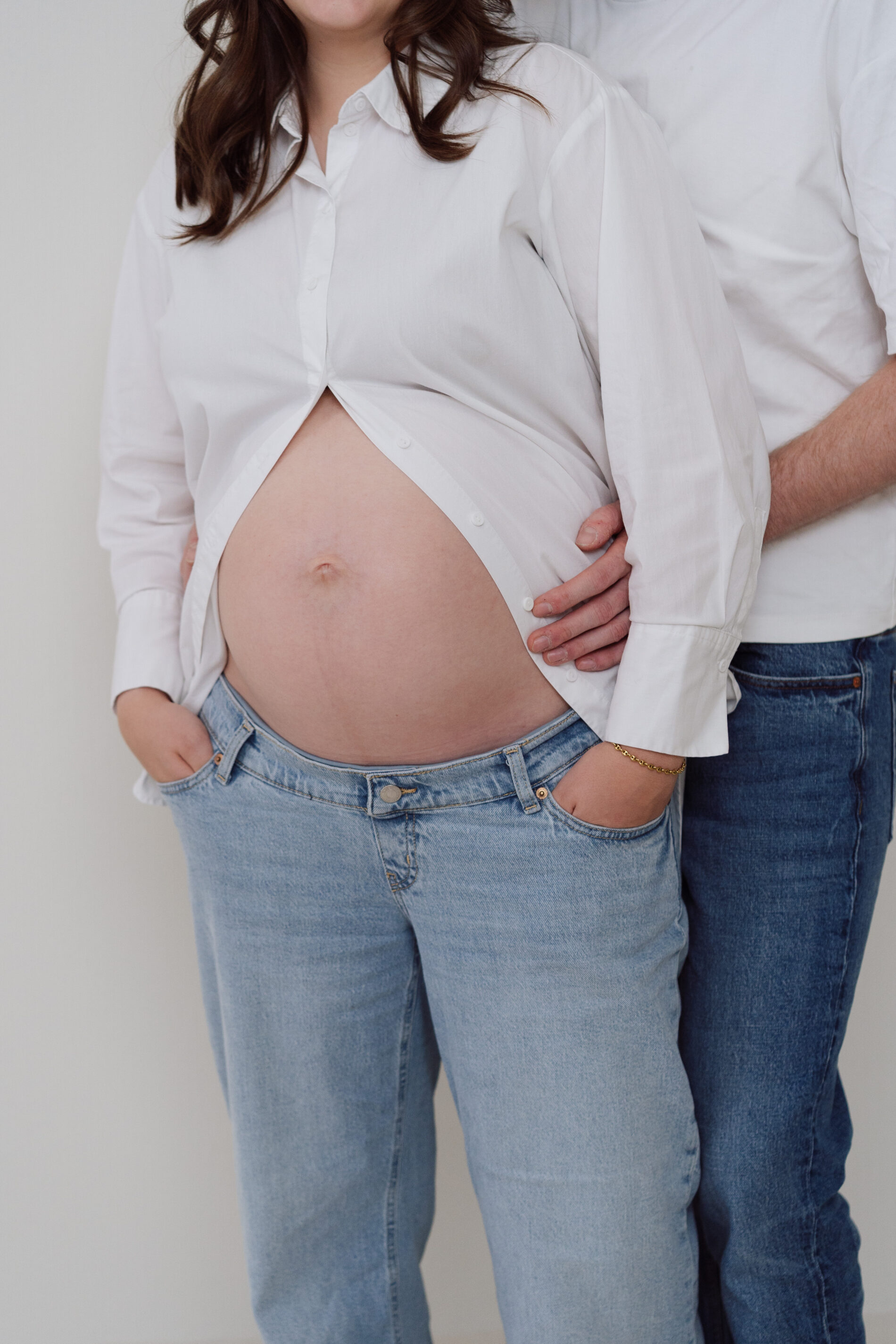 Babybauch Fotoshooting Münster – Hände haltend, Paar im Studio, natürliches Mini-Shooting