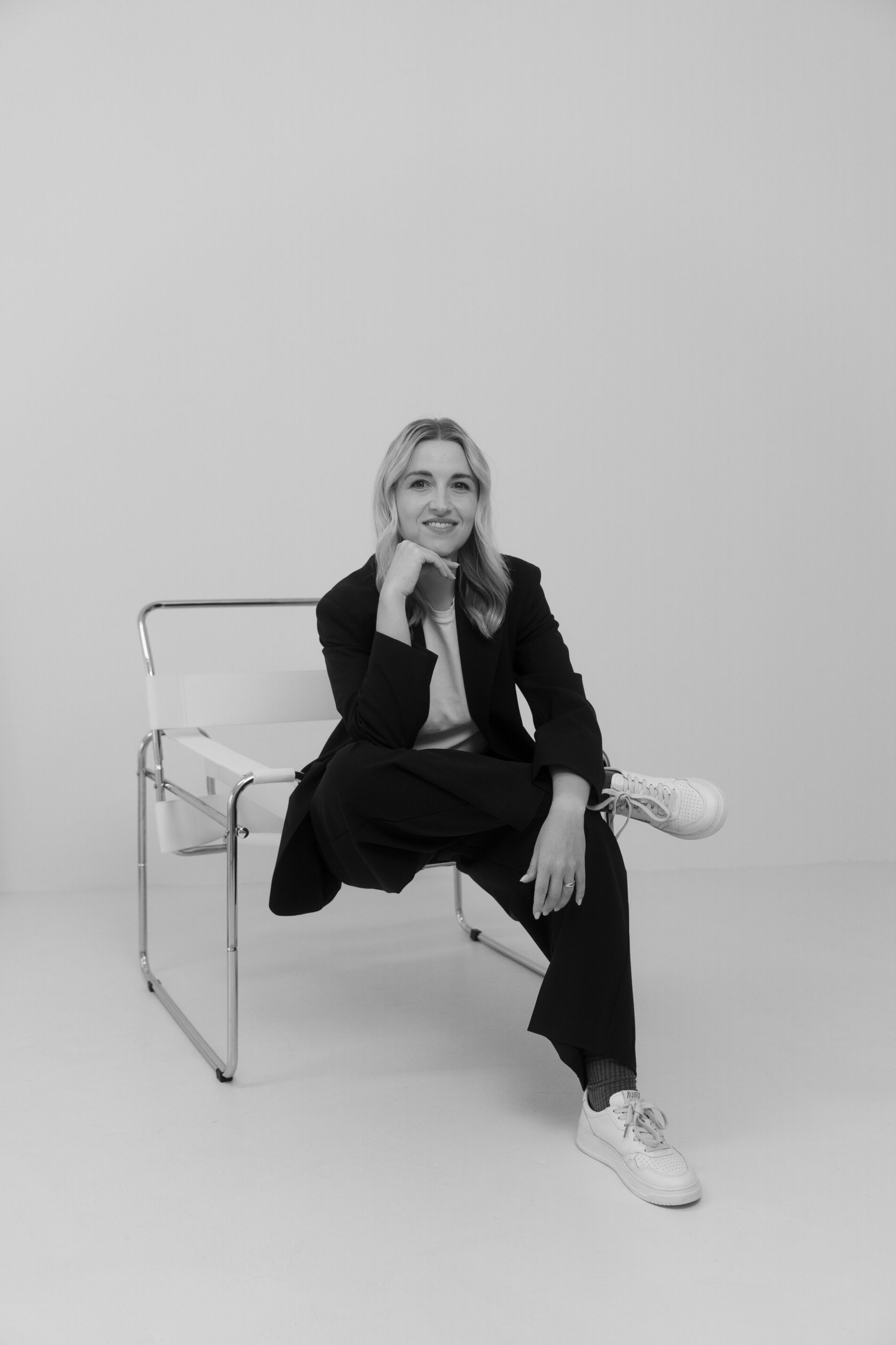 Modernes Fotoshooting Münster – Business Portrait einer Frau im schwarzen Anzug auf Designerstuhl